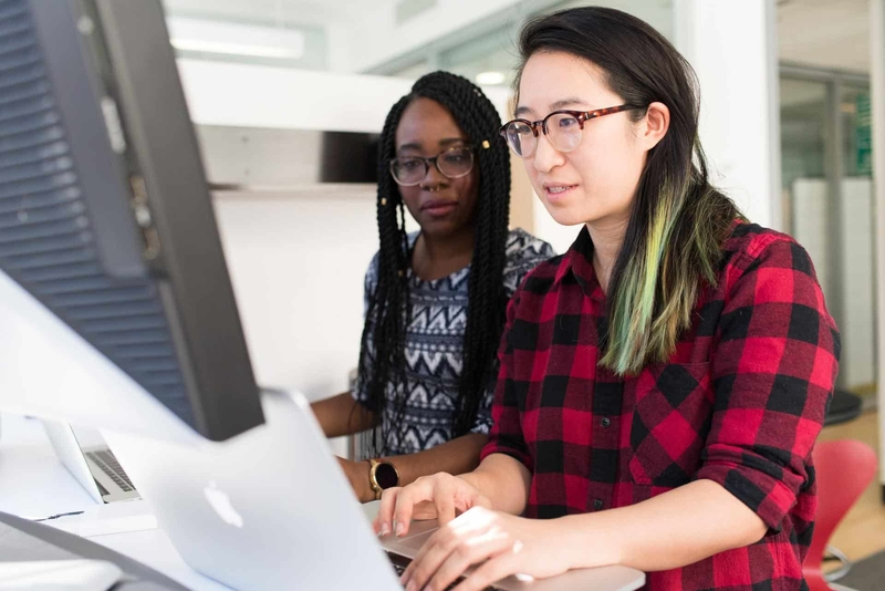 Two girls using a macbook