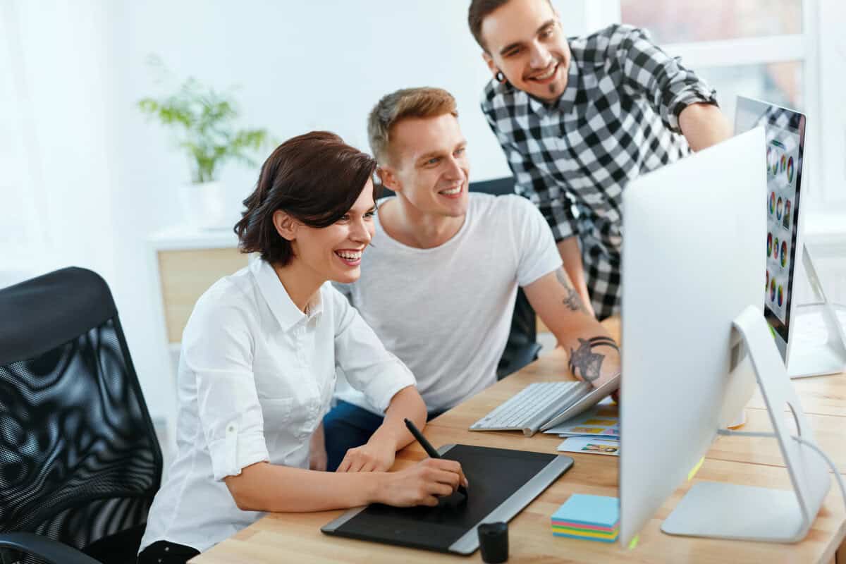 Graphic designer with tattoos working at a desk with a digital tablet and computer. testimonial