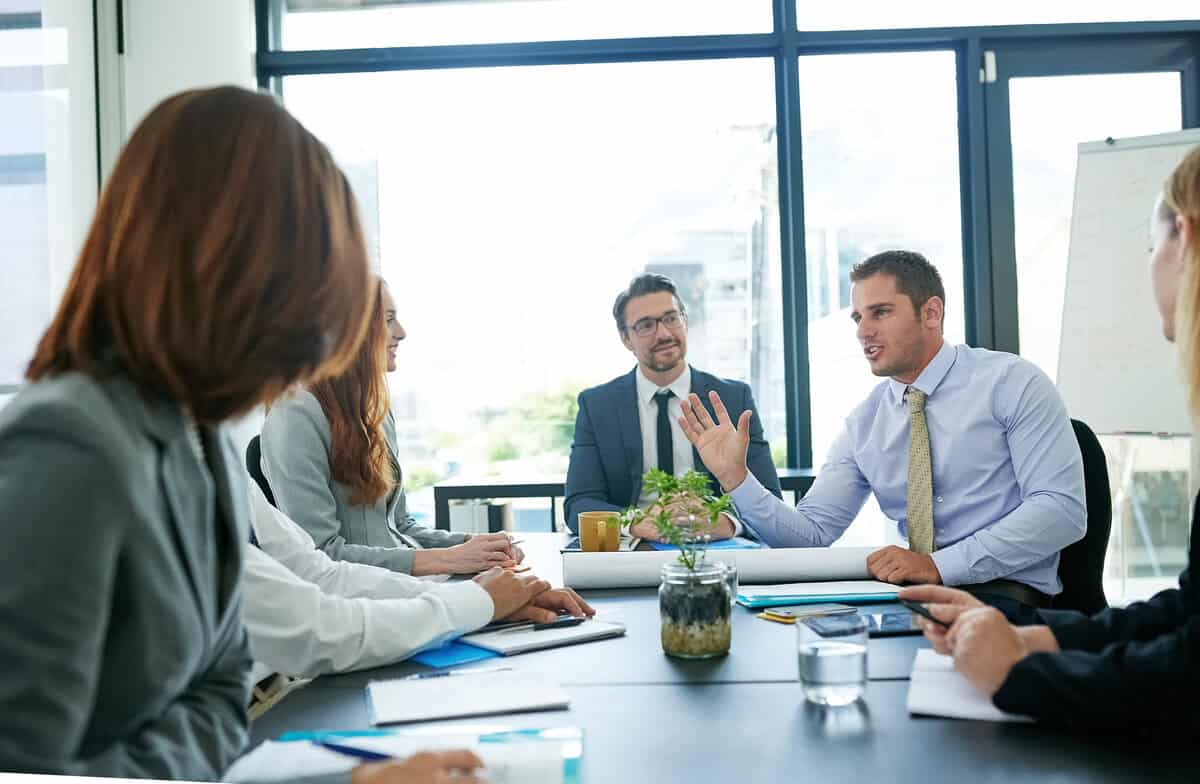 A group of professionals in a business meeting, collaborating around a table in a modern office. testimonial